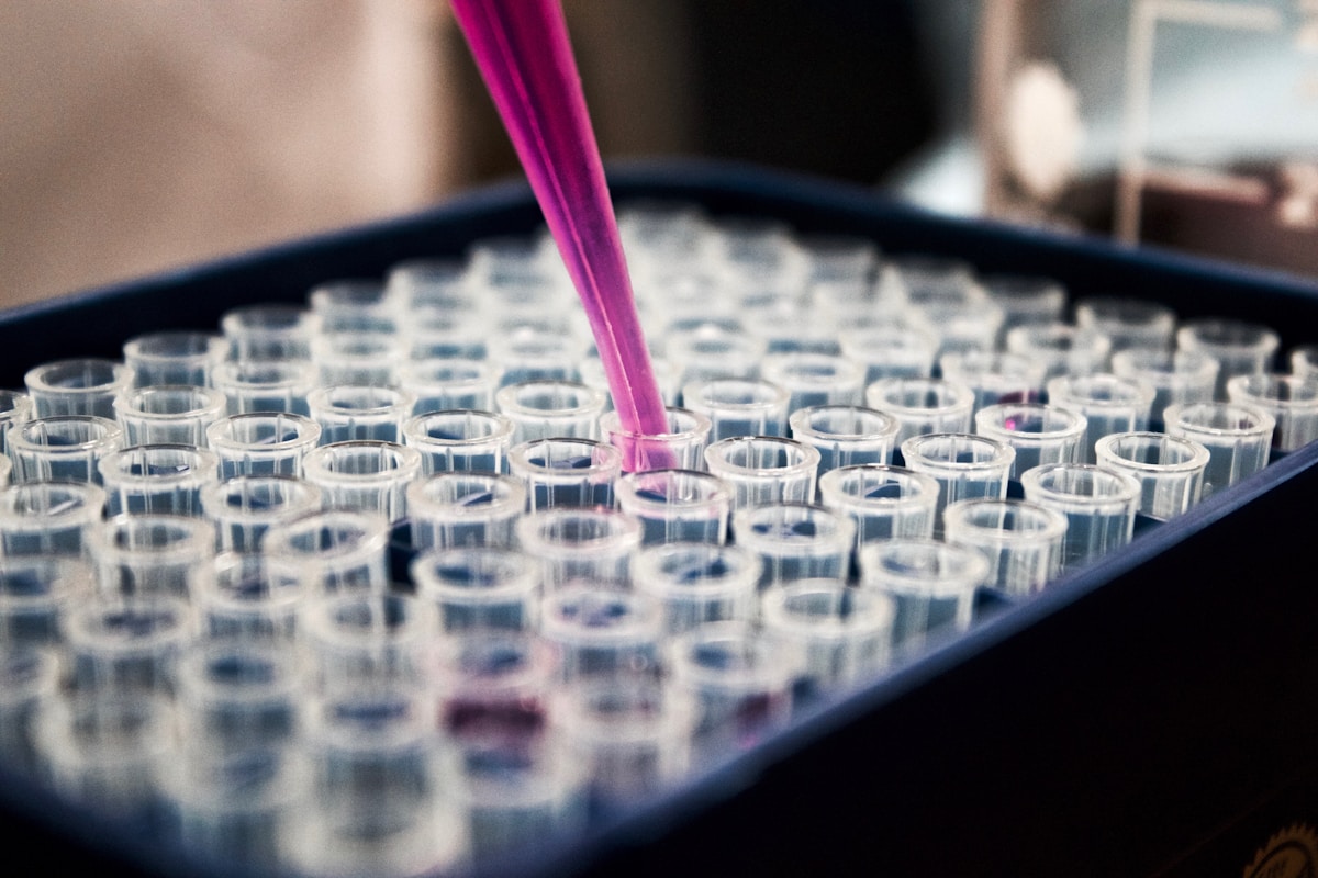 A real laboratory photograph with a pipette and rows of sample tubes.