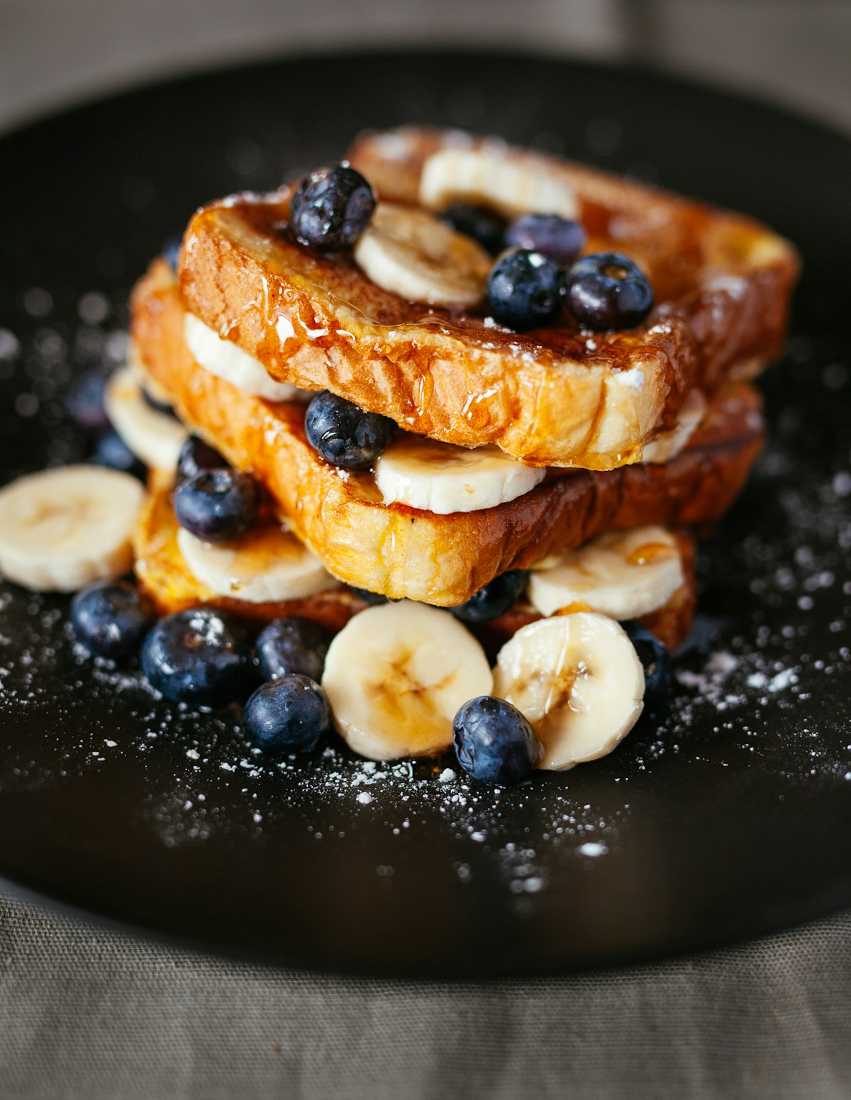 A real close-up photograph of stacked pancakes, fruit, and syrup.